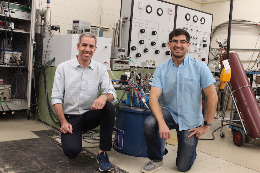 Aviram Uri and Sergio C. de la Barrera pose for a photo, each kneeling on one knee in a laboratory.