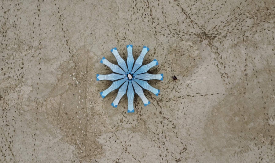 Aerial view of Living Knitwork Pavilion. The 12 panels are joined in the center to form a dodecagonal pyramid. Trails of footsteps can also be seen in the sand.