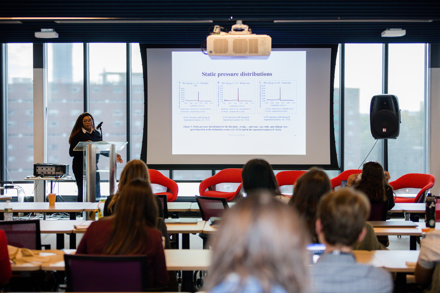 A woman at a lectern presents a slide labeled "Static pressure distributions" to an audience