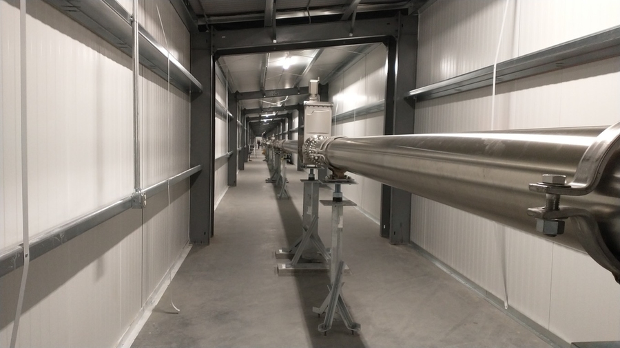An incredibly long LIGO hallway has a long metallic tube going down it.