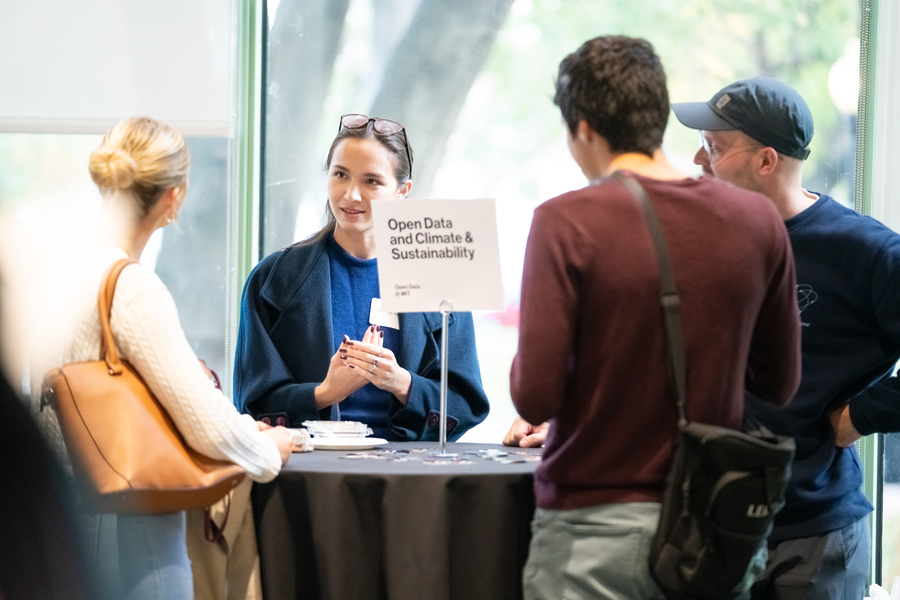 Four people are gathered around a small table and talking in Hayden Library; a sign on the table reads "Open Data and Climate & Sustainability."