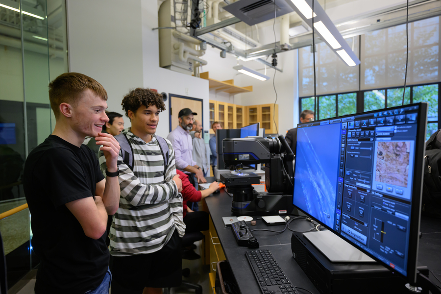 Two MIT students view the monitor of a digital optical microscope.