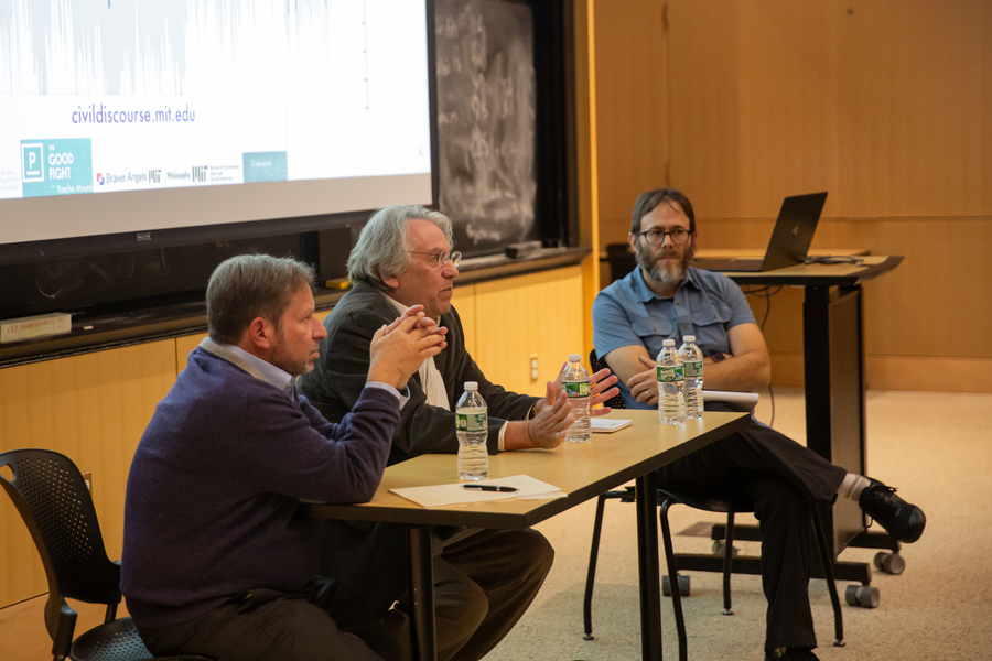 Steve Koonin, Kerry Emanuel, and Brad Skow sit around a folding table. A slide is visible on the wall behind them with a web address, civildiscourse.mit.edu.