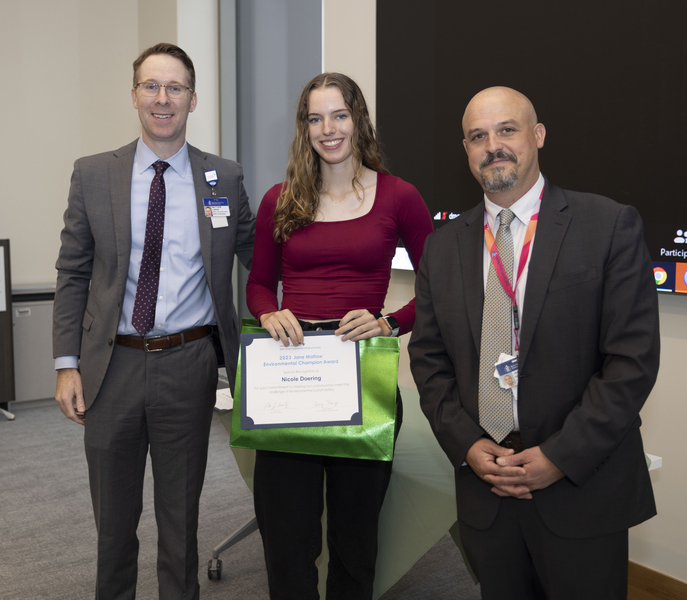 Nicole Doering holding her award and posing indoors between Matt Larkin and Jarrod Dore 