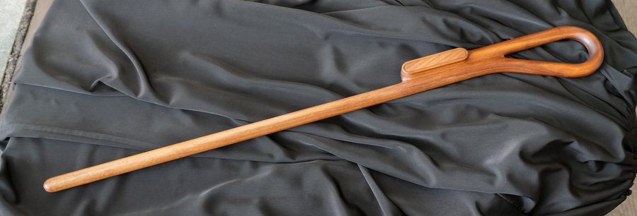 A wooden staff lying on a black cloth.