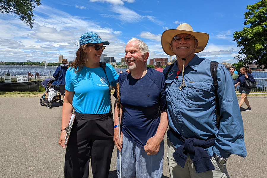 On a sunny summer day along a riverbank, Laura Jasinski, Paul Parravano, and Steve Kropper pose for a photo.