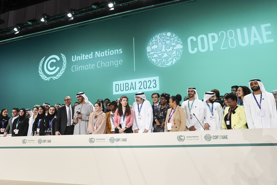 Approximately 35 delegates stand on stage, posing for this photo