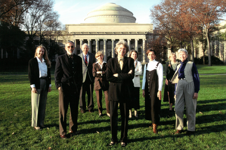 Several women and two men stand in a group on a sunny day with the MIT dome behind