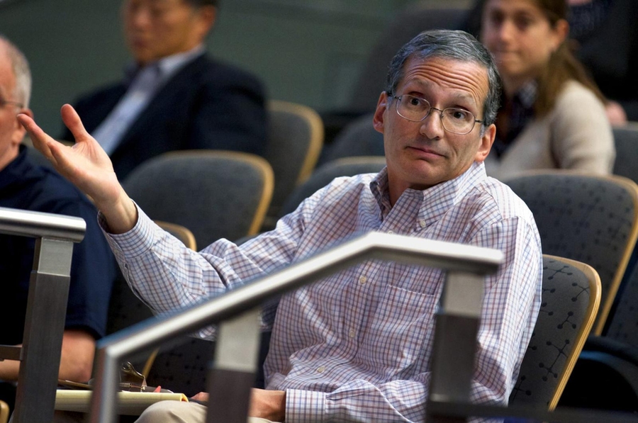 A photo of Richard M. Wiesman, seated and gesturing, in a classroom at MIT.