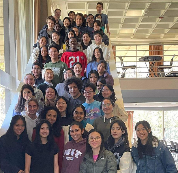 About 50 students pose together while standing on a large staircase