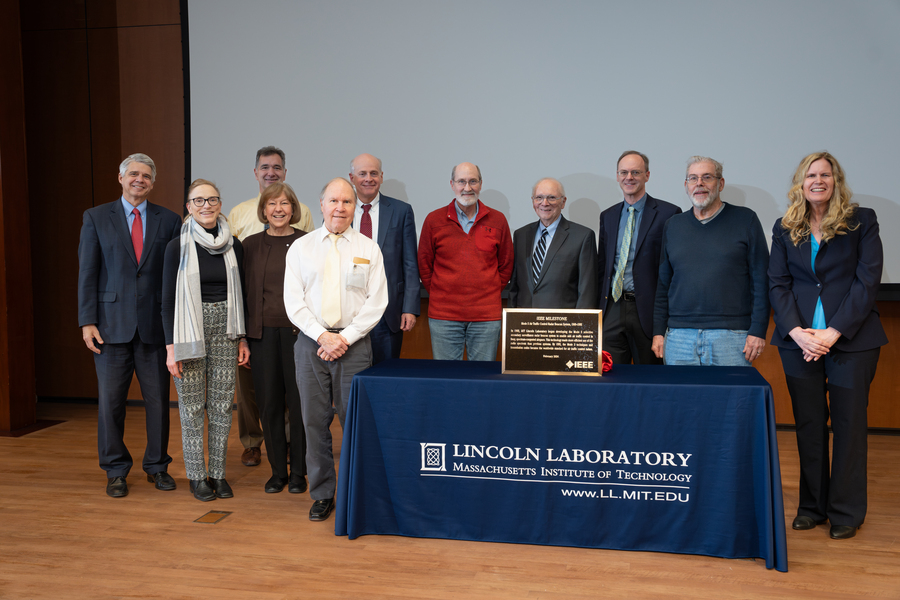 Eleven people pose around a table with the Mode S IEEE plaque on it.