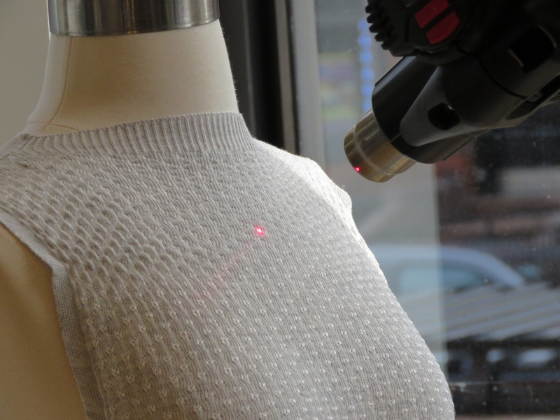 Close-up of a dress neckline on a mannequin being targeted by a laser