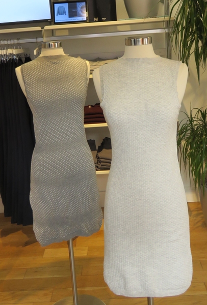 Photo if two armless and headless mannequins, each wearing a sleeveless knit dress, one grey and one white