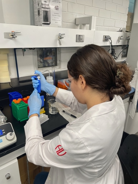Over-the-shoulder view of Favianna Colón Irizarry working at a lab