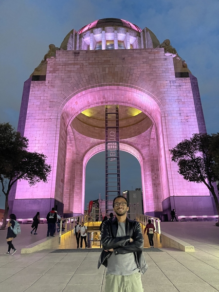 Matt Smith stands in front of a large arch monument at night.