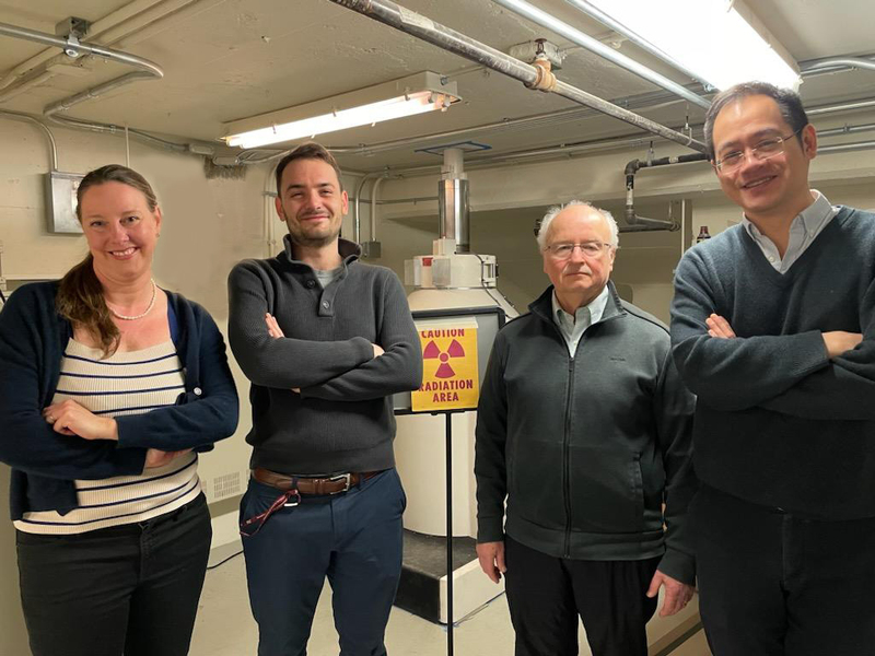 Jennifer Rupp, Thomas Defferriere, Harry Tuller, and Ju Li pose standing in a lab, with a nuclear radiation warning sign in the background