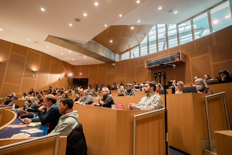 View of audience members in a lecture hall, who look to be listening intently to the panel discussions.