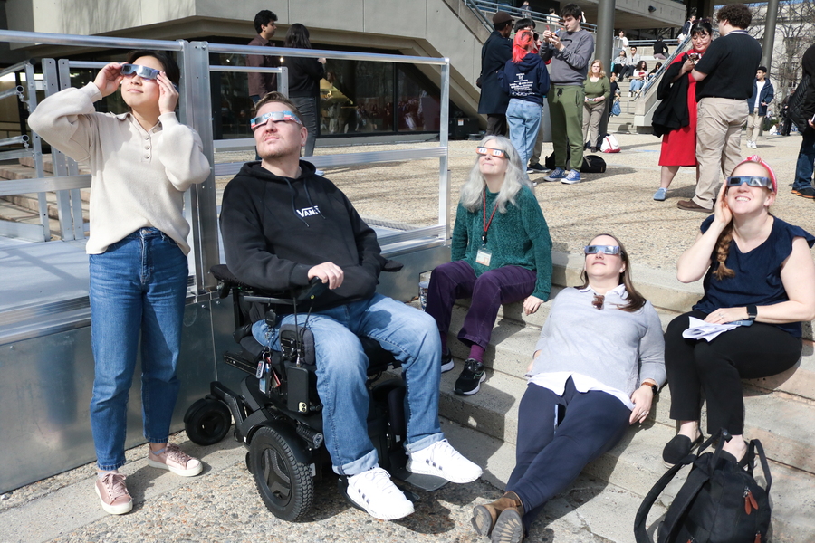 5 people, including one in a wheelchair, look up at the eclipse