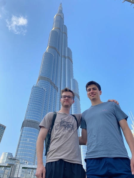 Ground-level shot looking up at two men in front of  Dubai’s Burj Khalifa