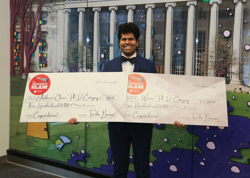 Bhavish Dinakar holding two oversized checks representing his prizes.