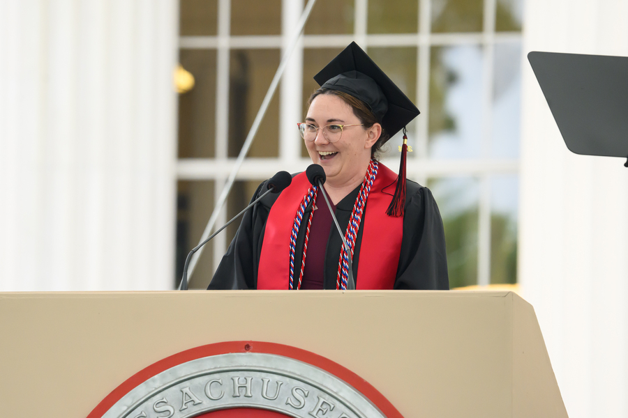 Mikala Molina, wearing cap and gown, speaks at a podium