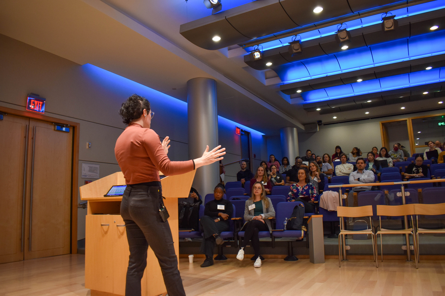 Kiara Eldred seen from behind standing in front of room, presenting.
