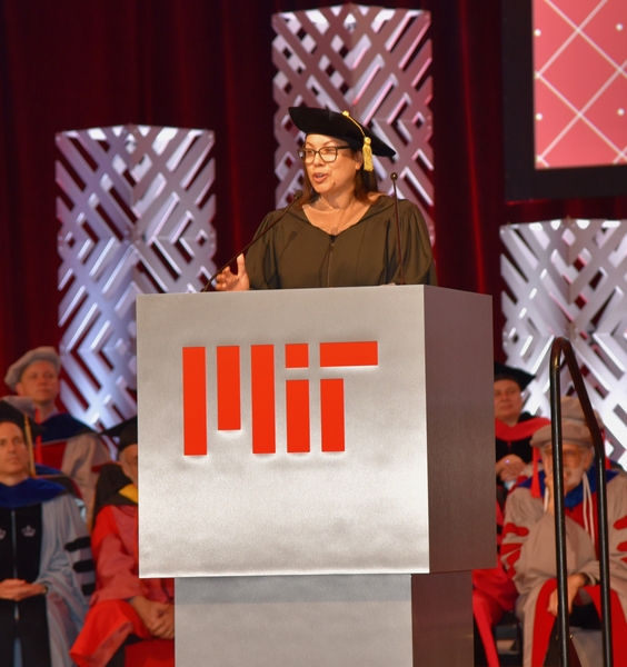 Diane Hoskins speaks on an indoor stage, at a lectern bearing MIT’s logo