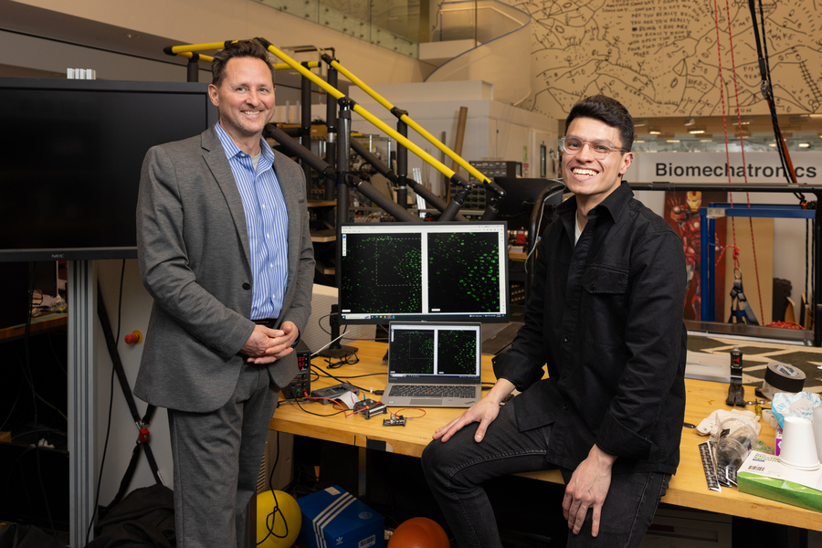 Hugh Herr and Guillermo Herrera-Arcos smile while inside their busy Media Lab space, full of computers are projects.