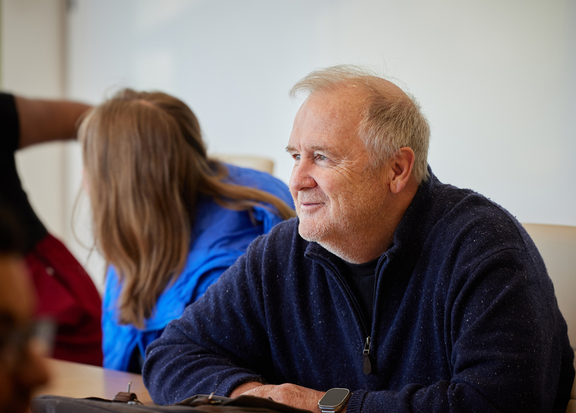 A head-and-shoulders portrait of Craig Carter wearing a blue sweater, leaning forward and looking off to the left.