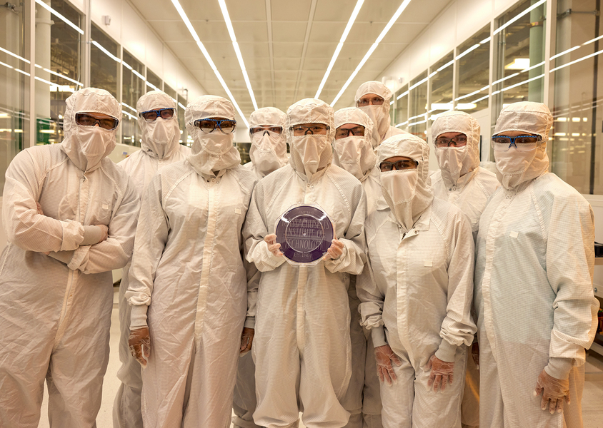 Ten people clad in white protective clothing covering all but their eyes, which are behind safety glasses, pose as a group inside a nanotechnology cleanroom.