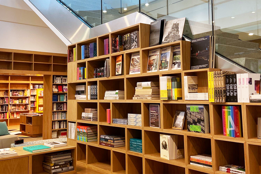 Photo of MIT Press Book Store shelves nestled beneath a glass stairwell