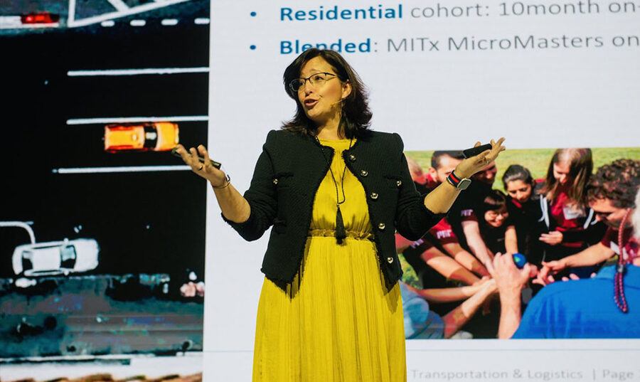 Photo of a woman speaking in front of a projected slide