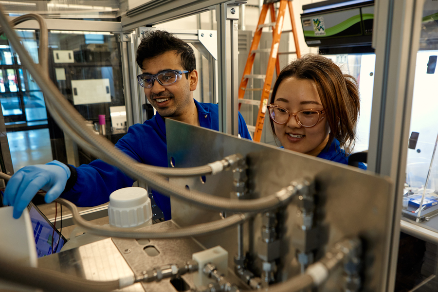 Two workers operate a machine