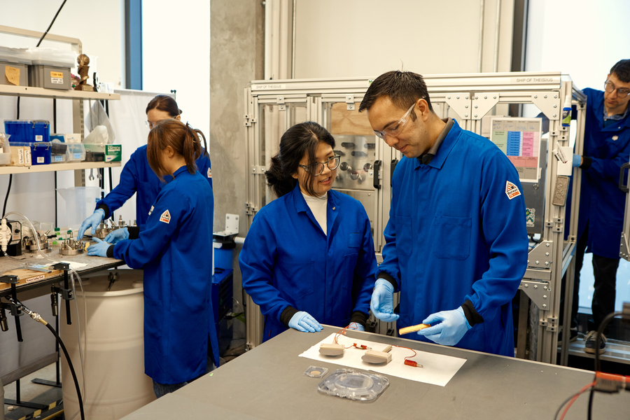 Two workers at SiTration discuss a device at a table in the lab. 