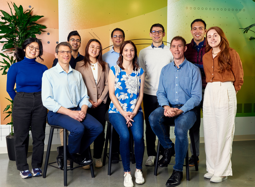 10 people pose, smiling, in two rows