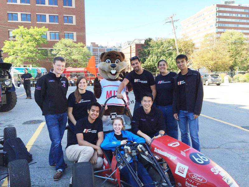 8 teammates pose with their car and Tim the Beaver