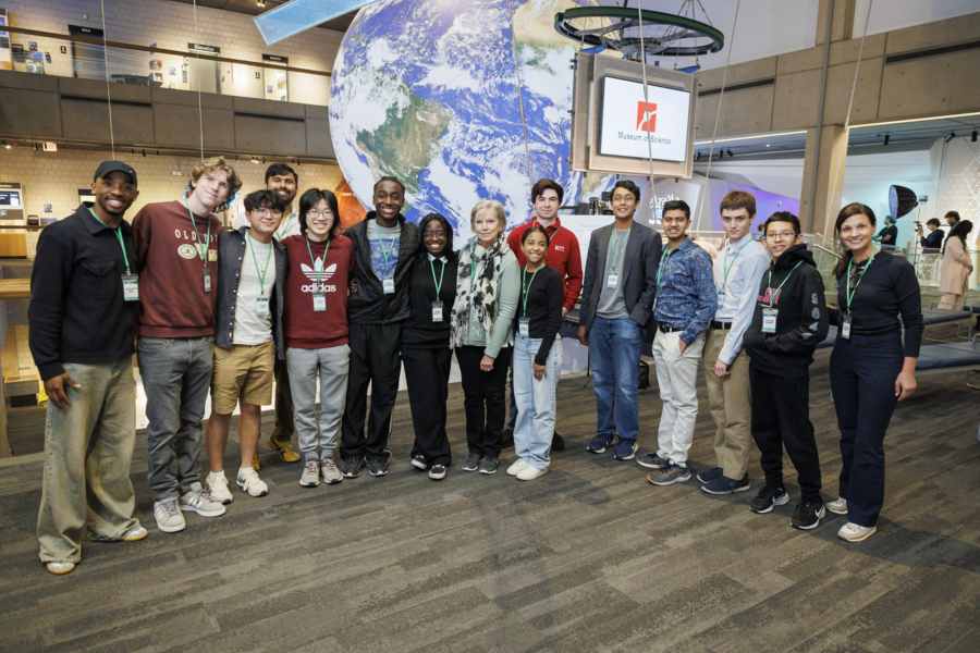 Fourteen students pose with a large model of the planet Earth behind them.