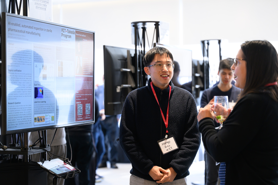 Graduate student Zhengqi Gao standing in front of a screen displaying his research.