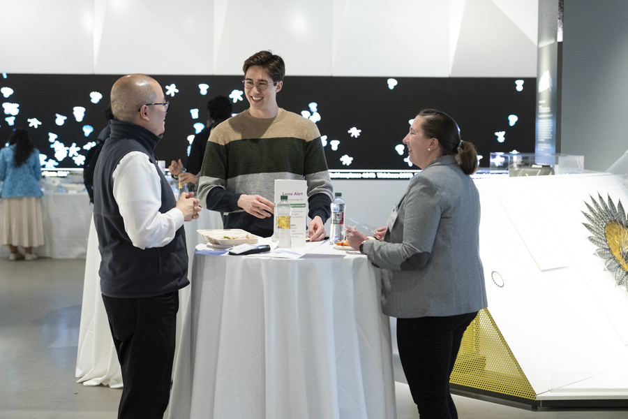 Three people having a conversation while standing at a table.