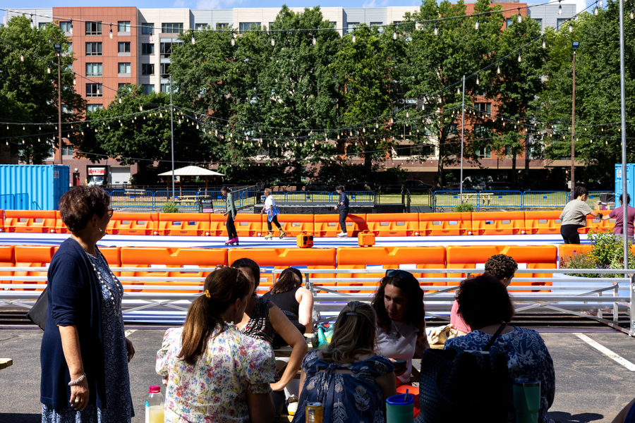 People sit around a picnic table in front of an outdoor roller rink.