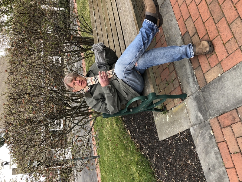 A photo of Professor John Vander Sande in a coat sitting on a park bench