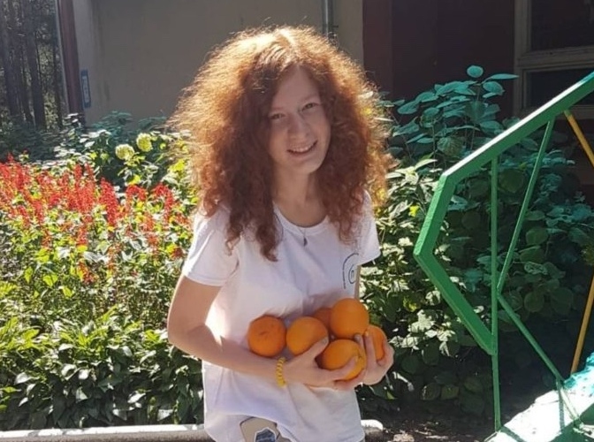 Yulia Zdanovska stands in a garden with an armload of oranges