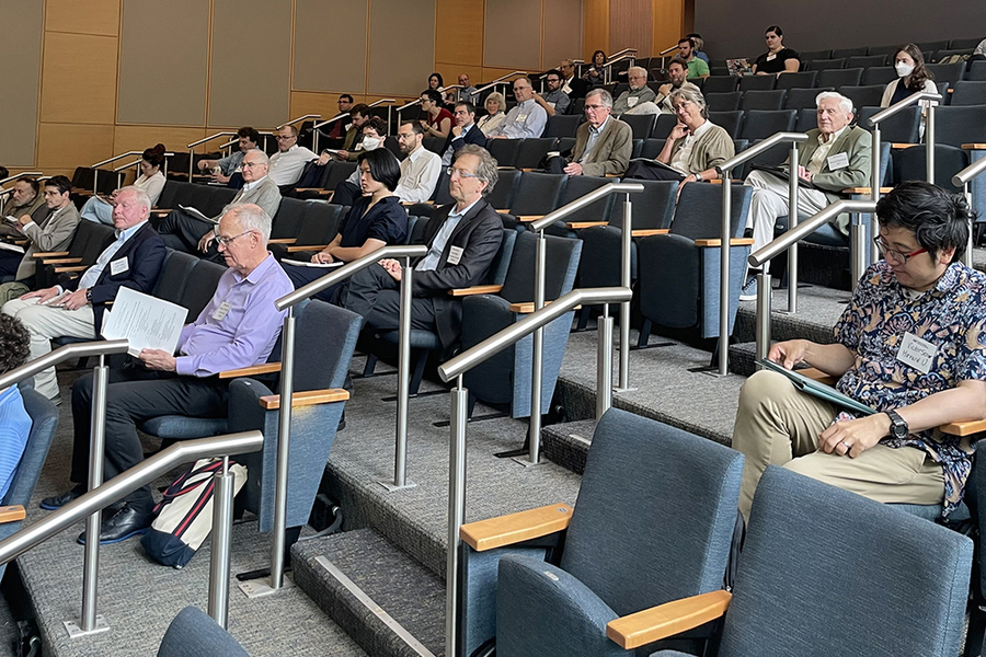 An audience in stadium-style seating listens to an unpictured speaker