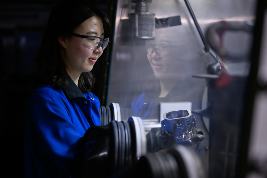 Side view of So Yeon Kim manipulating something indistinct inside a glovebox