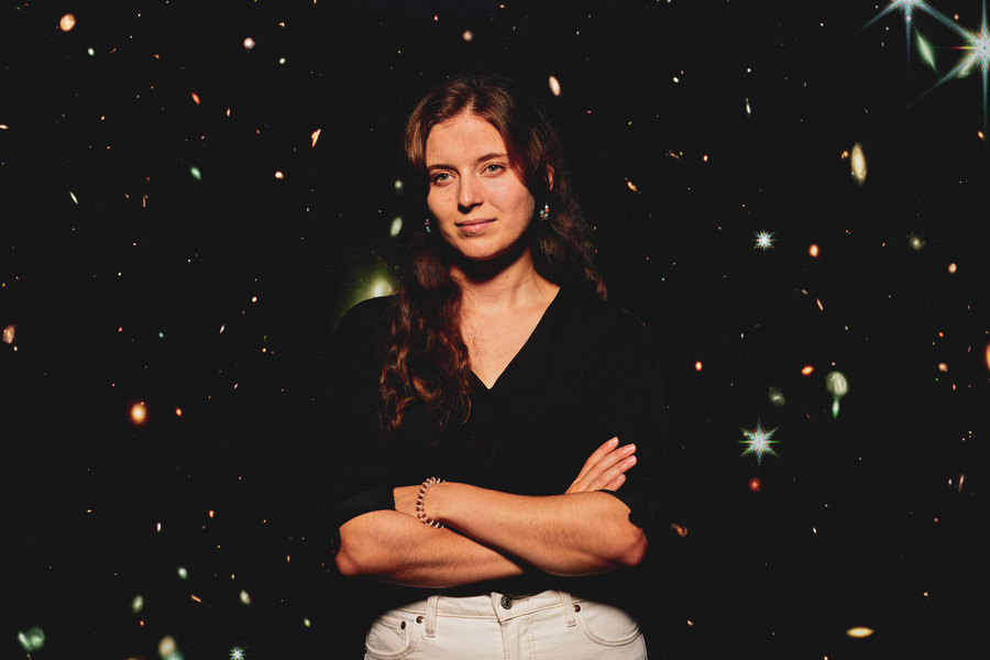 Dominika Ďurovčíková stands in front of a giant photo of a galaxy.