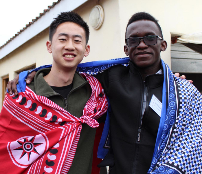 Daniel Zhang and Martin Lubowa pose for a photo while wearing a red and blue Swazi outfits.
