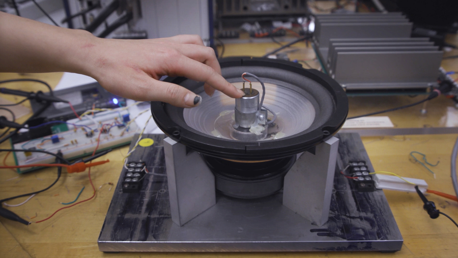 A hand is shown touching a loudspeaker with parts exposed