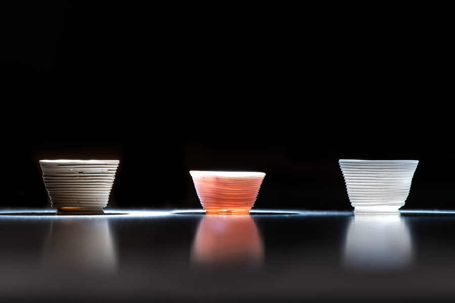 Three 3d-printed glass cups are illuminated from underneath, showing off their different colors.