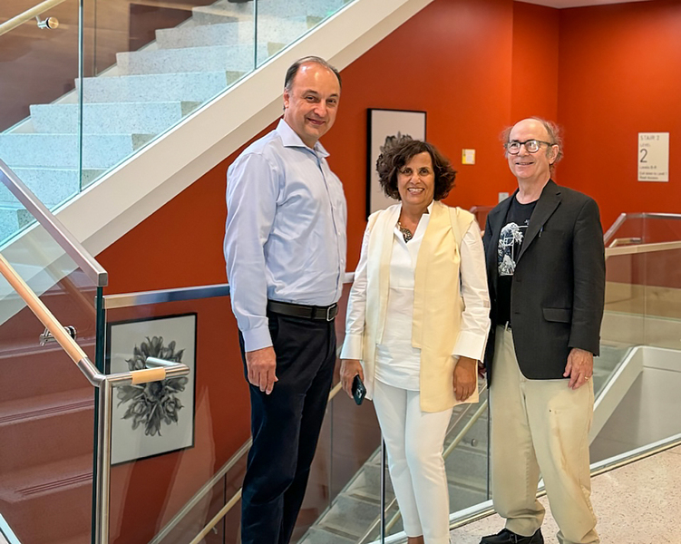 Vladimir Bulović, Denise Milan, and Frank Wilczek pose together in front of a staircase, with framed artwork on the walls.