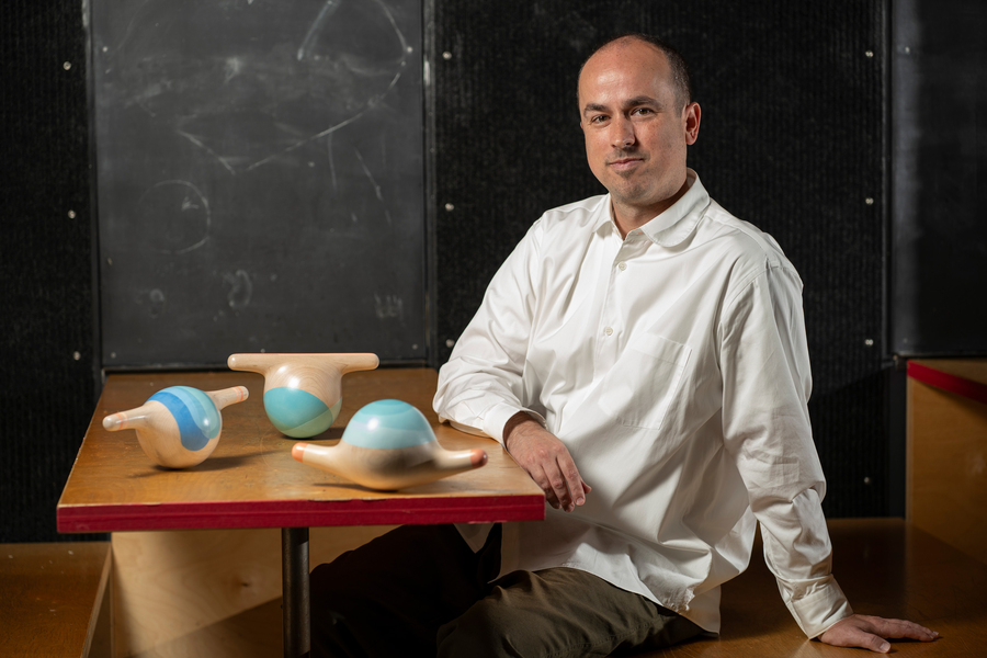 Brandon Clifford sits at a table with bulbous wobbly sculptures.
